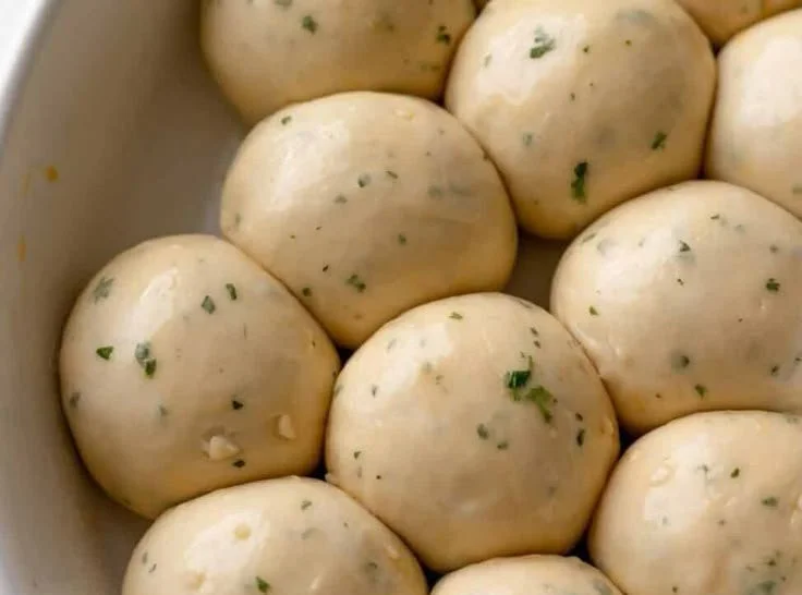 Freshly baked garlic bread rolls on a wooden cutting board