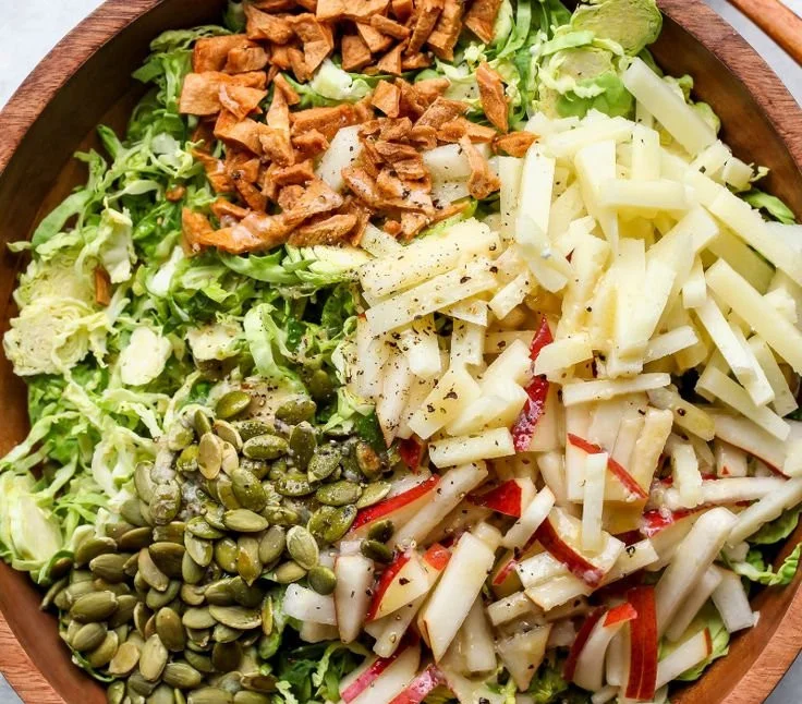 Shaved Brussels and Pear Salad garnished with nuts and cheese