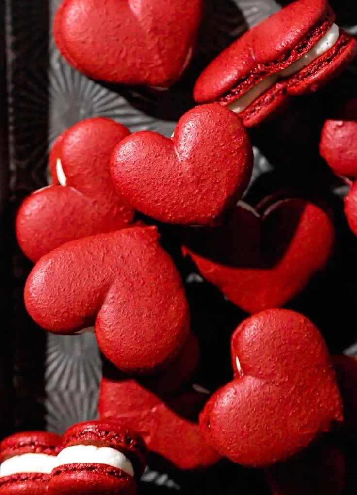 Delicious Red Velvet Macarons displayed on a rustic wooden table.