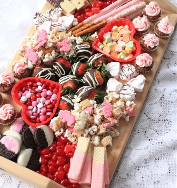 Valentine dessert charcuterie board filled with chocolates, berries, and treats