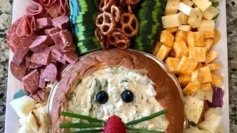 Festively arranged Easter charcuterie board with colorful cheeses and treats.